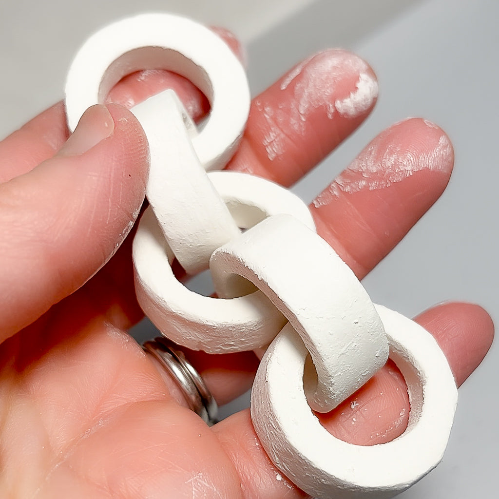 Hands holding handmade white porcelain rings during the crafting process