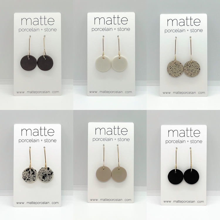 Set of six pairs of matte porcelain and stone earrings on branded cards.