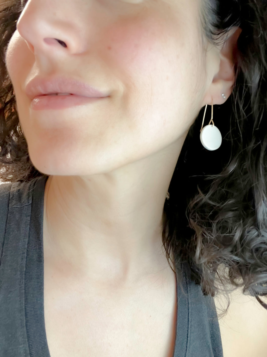 Close-up of a person wearing a white circular earring.