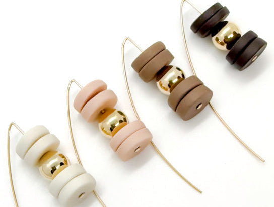 Four pairs of porcelain bead earring wires on a clean white background, featuring matte cream, blush pink, medium brown, and dark brown beads with shiny gold metallic accents.