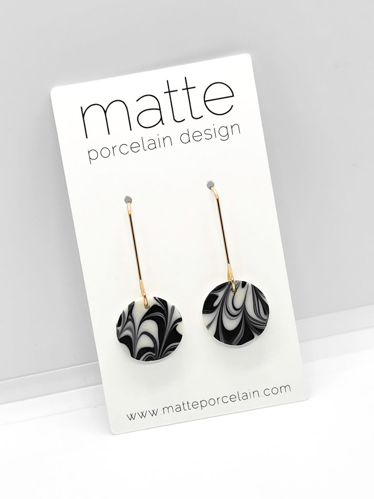 Black and white marbled earrings on a 'matte porcelain design' card with a gray background