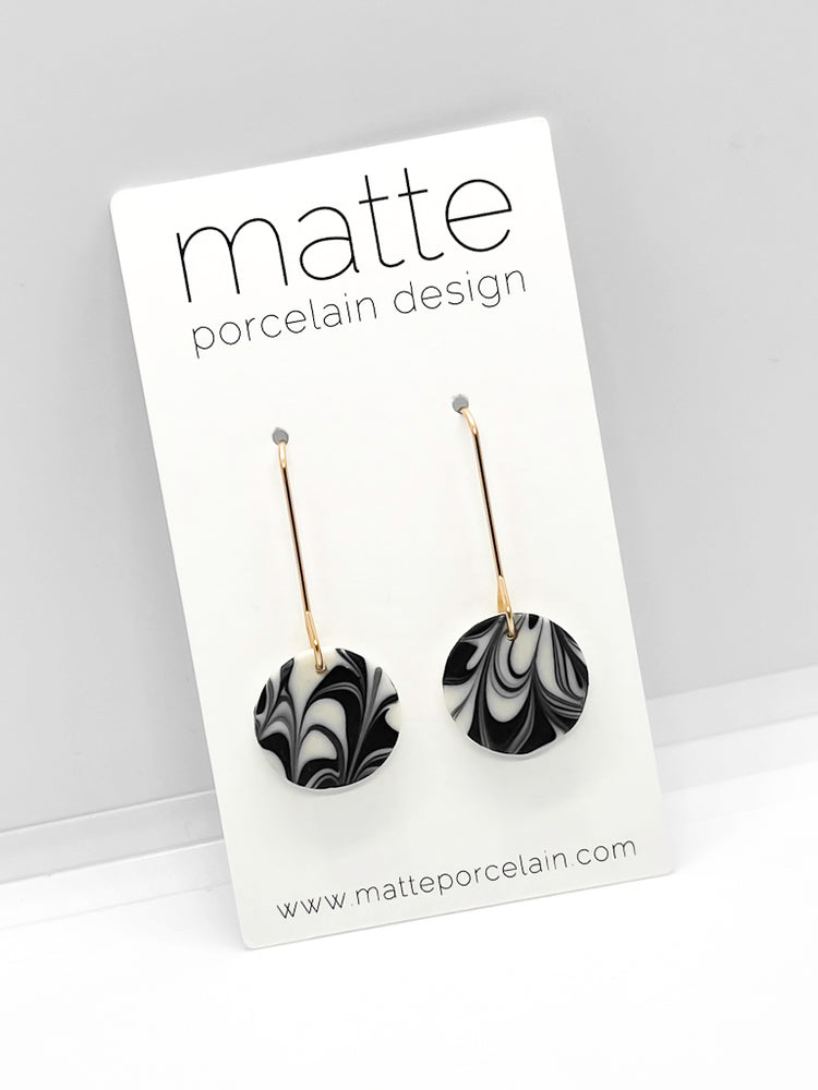 Black and white marbled earrings on a 'matte porcelain design' card with a gray background