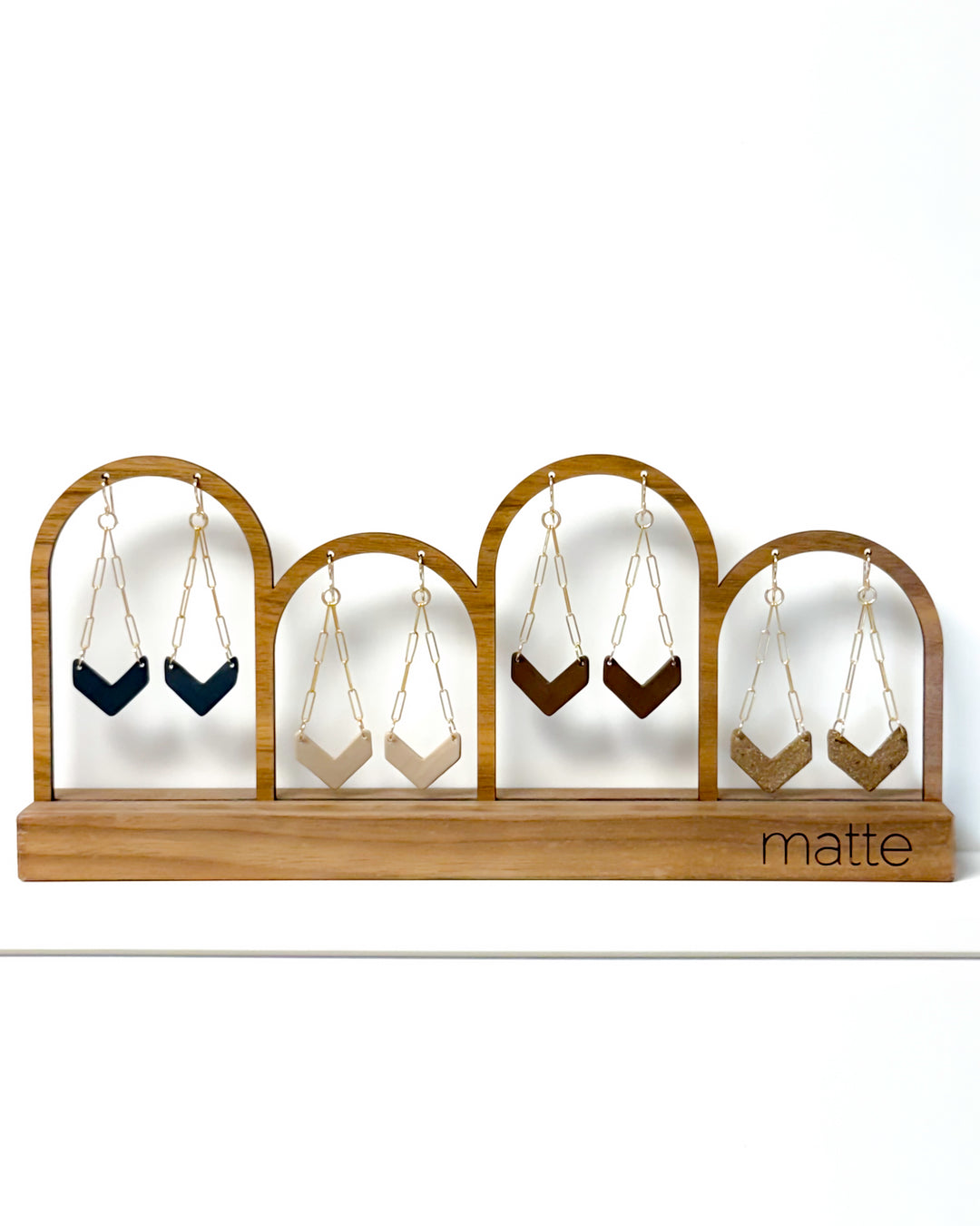 Wooden earring display with hanging earrings on a white background