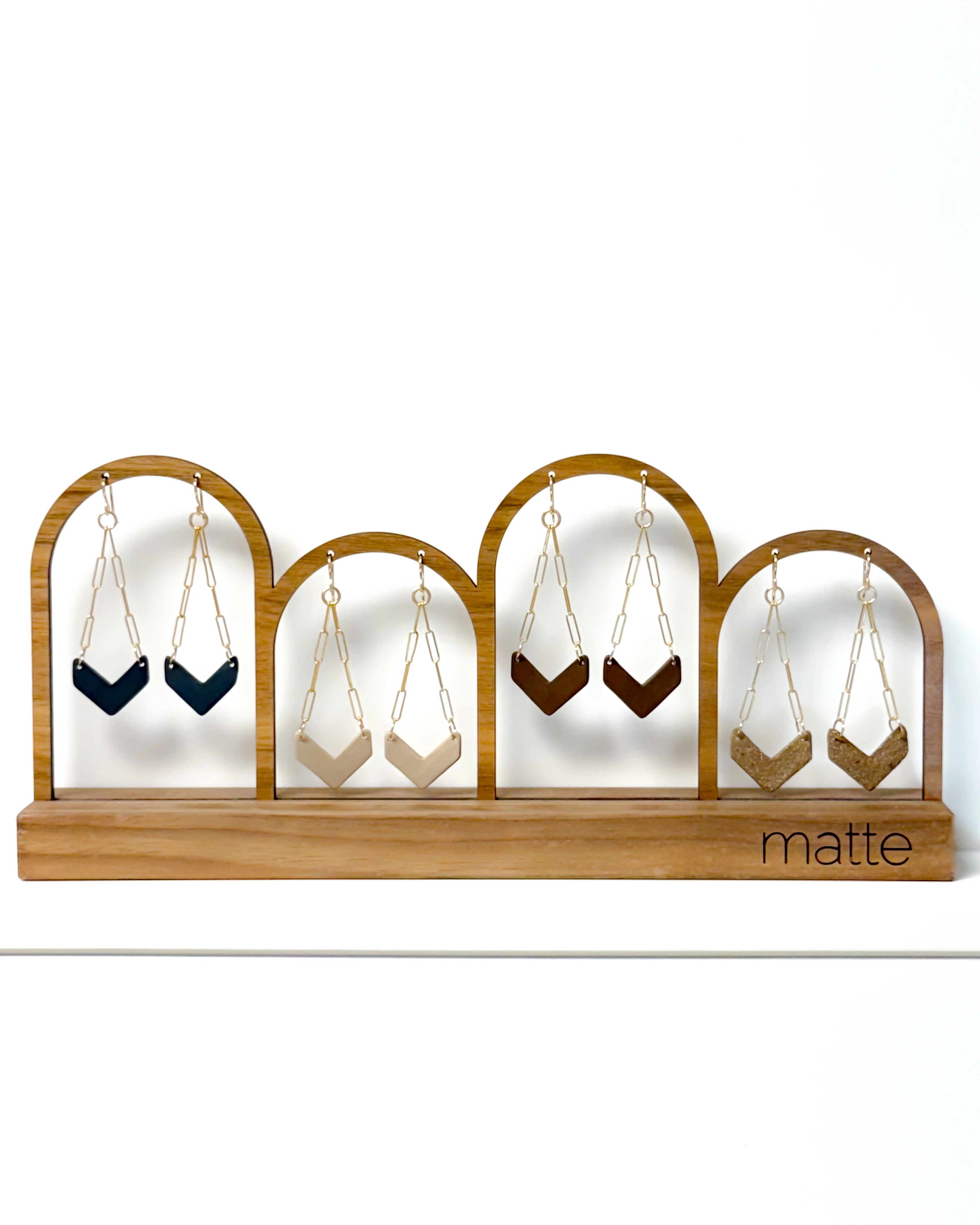 Wooden earring display with hanging earrings on a white background