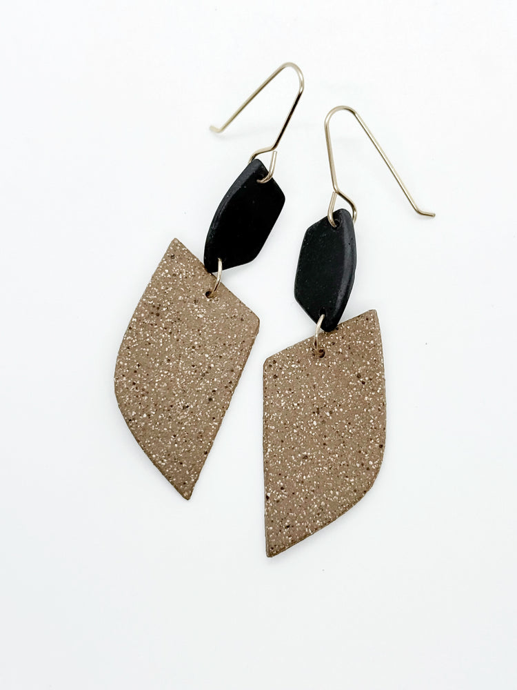 Pair of earrings with black and stoneware designs on a white background