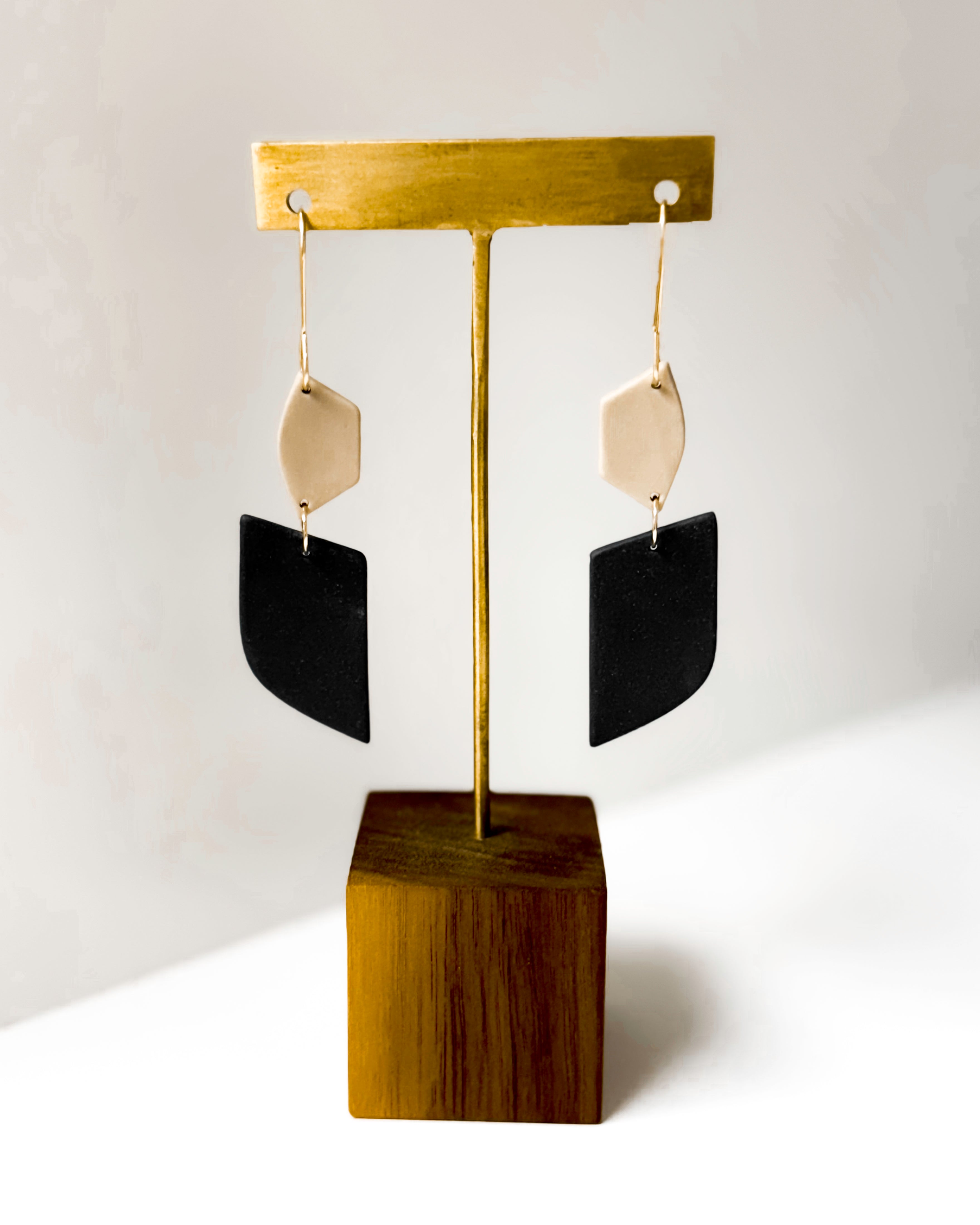 Earring stand with black and dune earrings on a white background