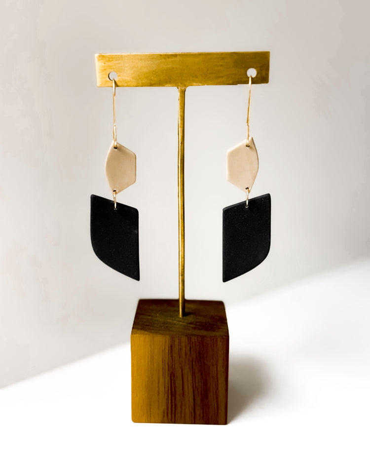 Earring stand with black and dune earrings on a white background