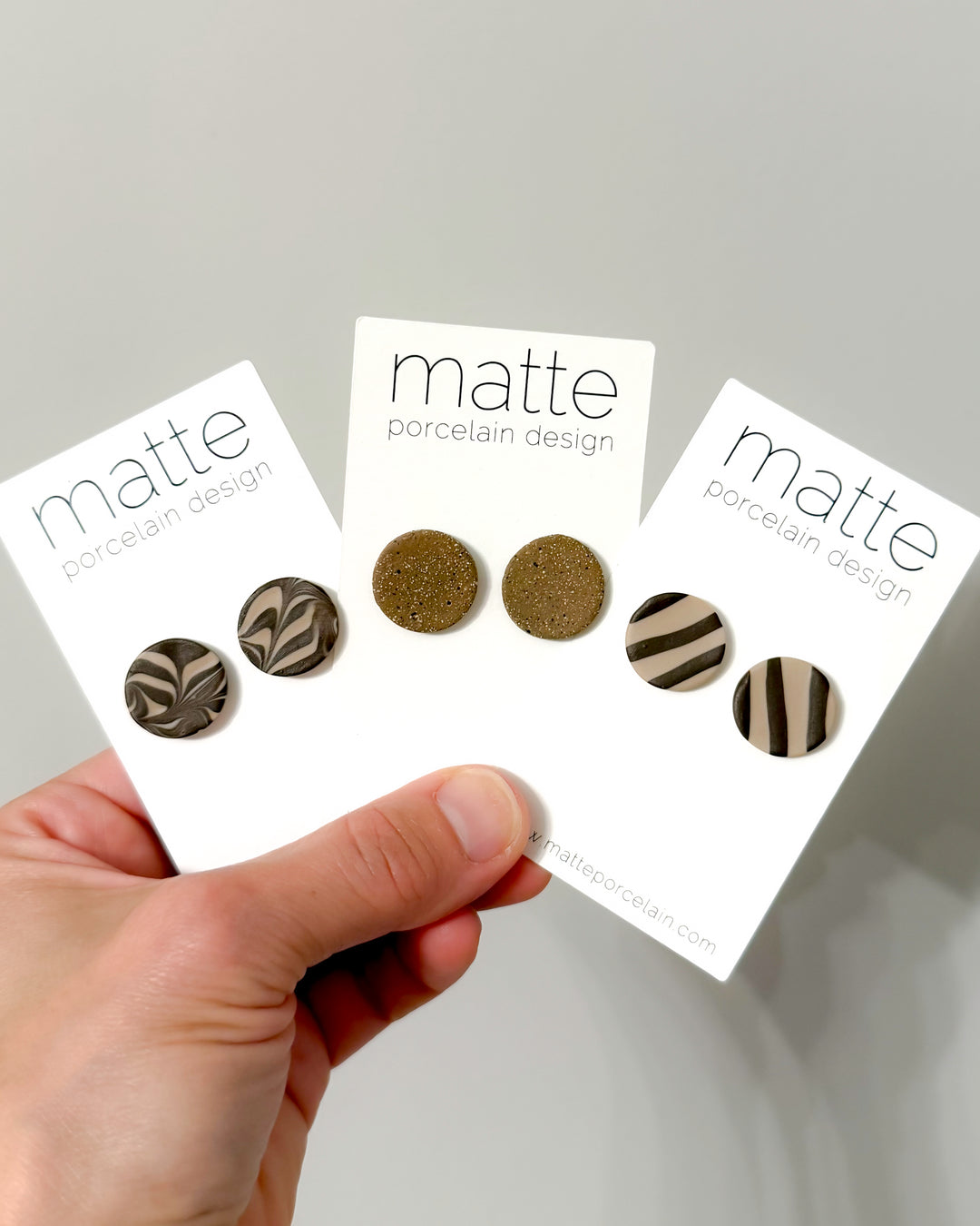Hand holding three cards displaying different color swatches with 'matte porcelain design' branding.