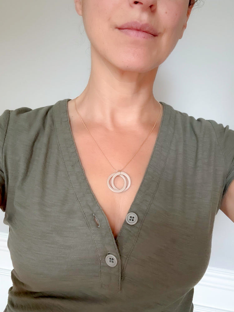 Person wearing a green shirt with a necklace featuring two interlocking circles.