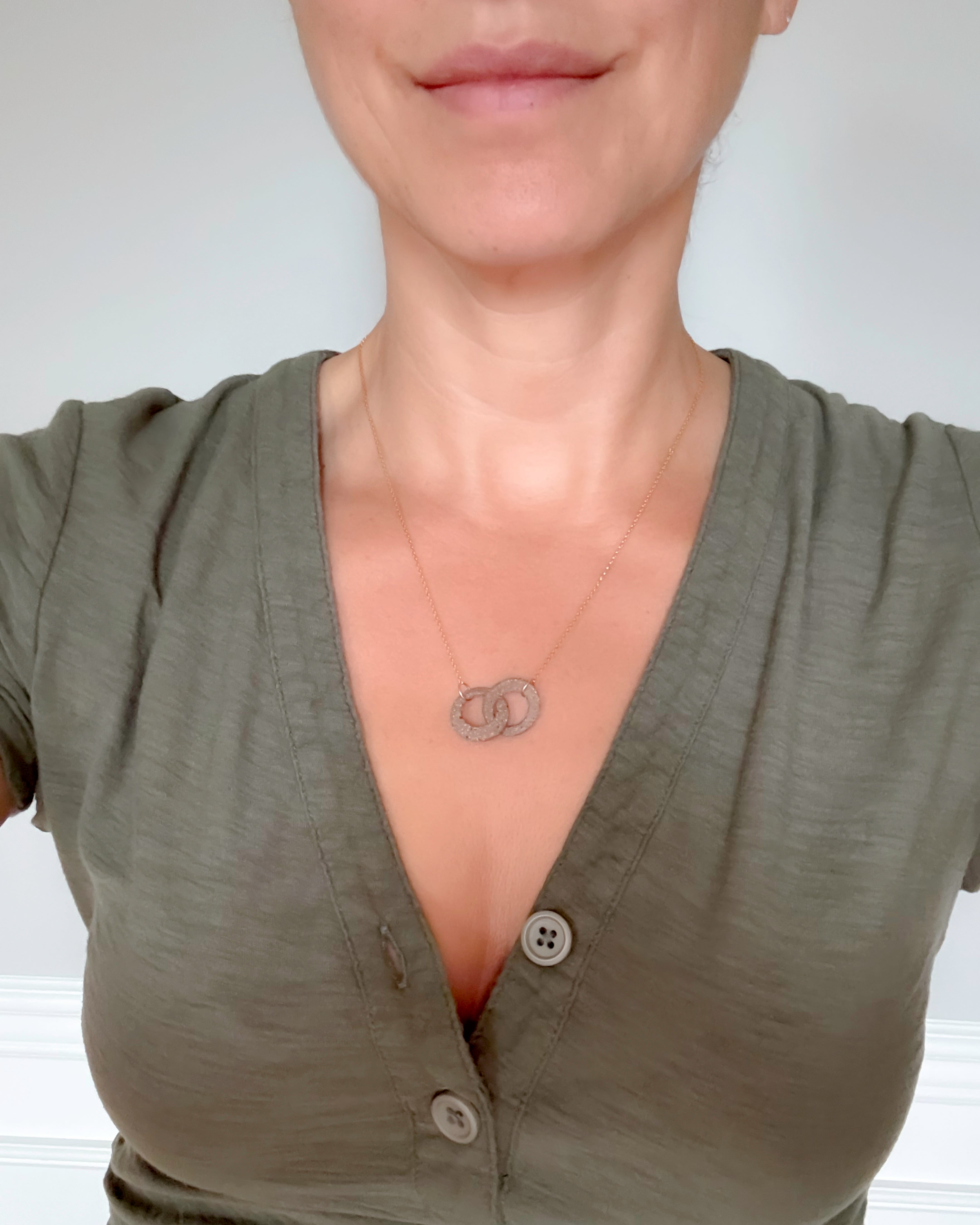 Person wearing a green shirt with a necklace featuring a circular pendant.