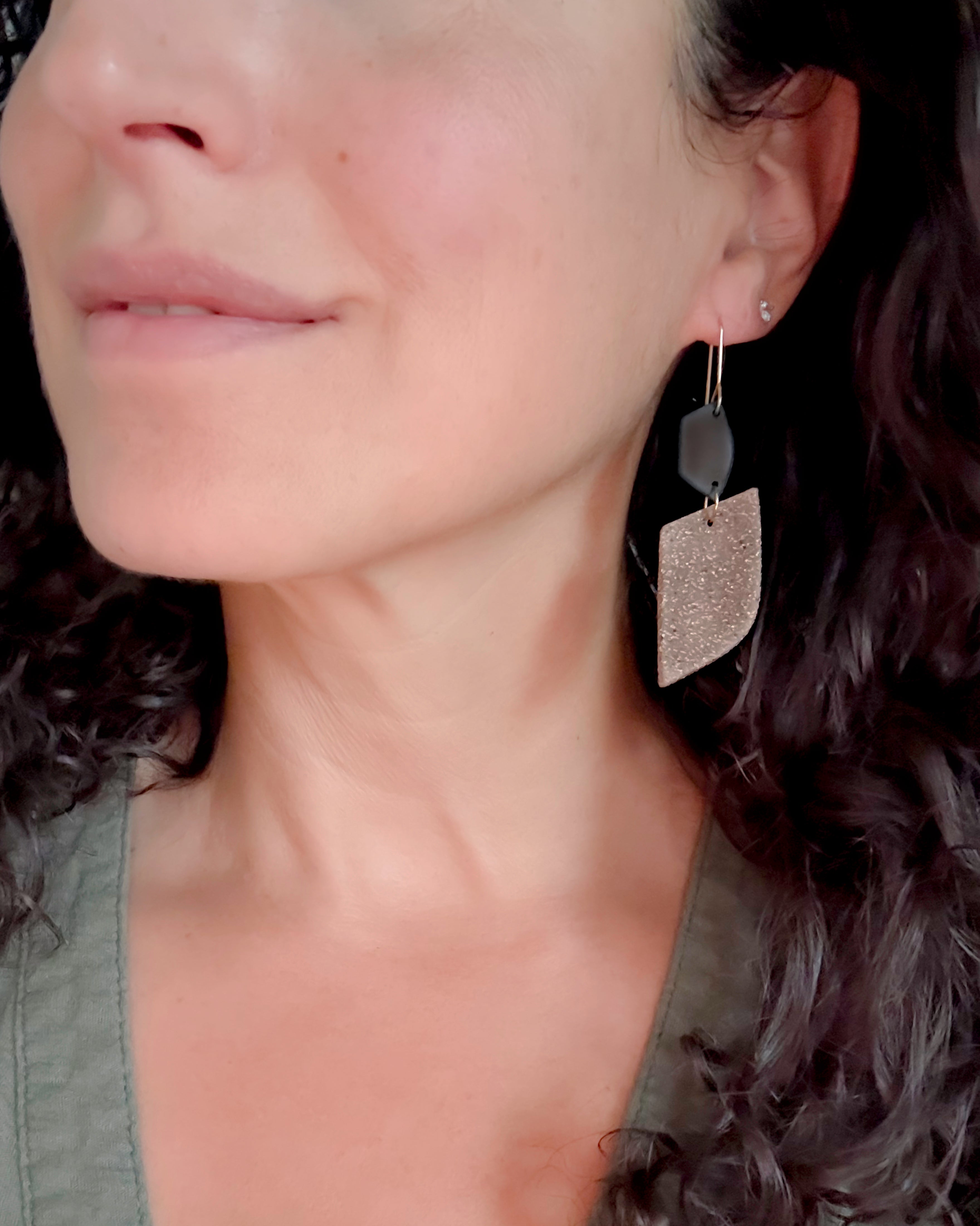 Close-up of a woman wearing gold earrings with a dark background