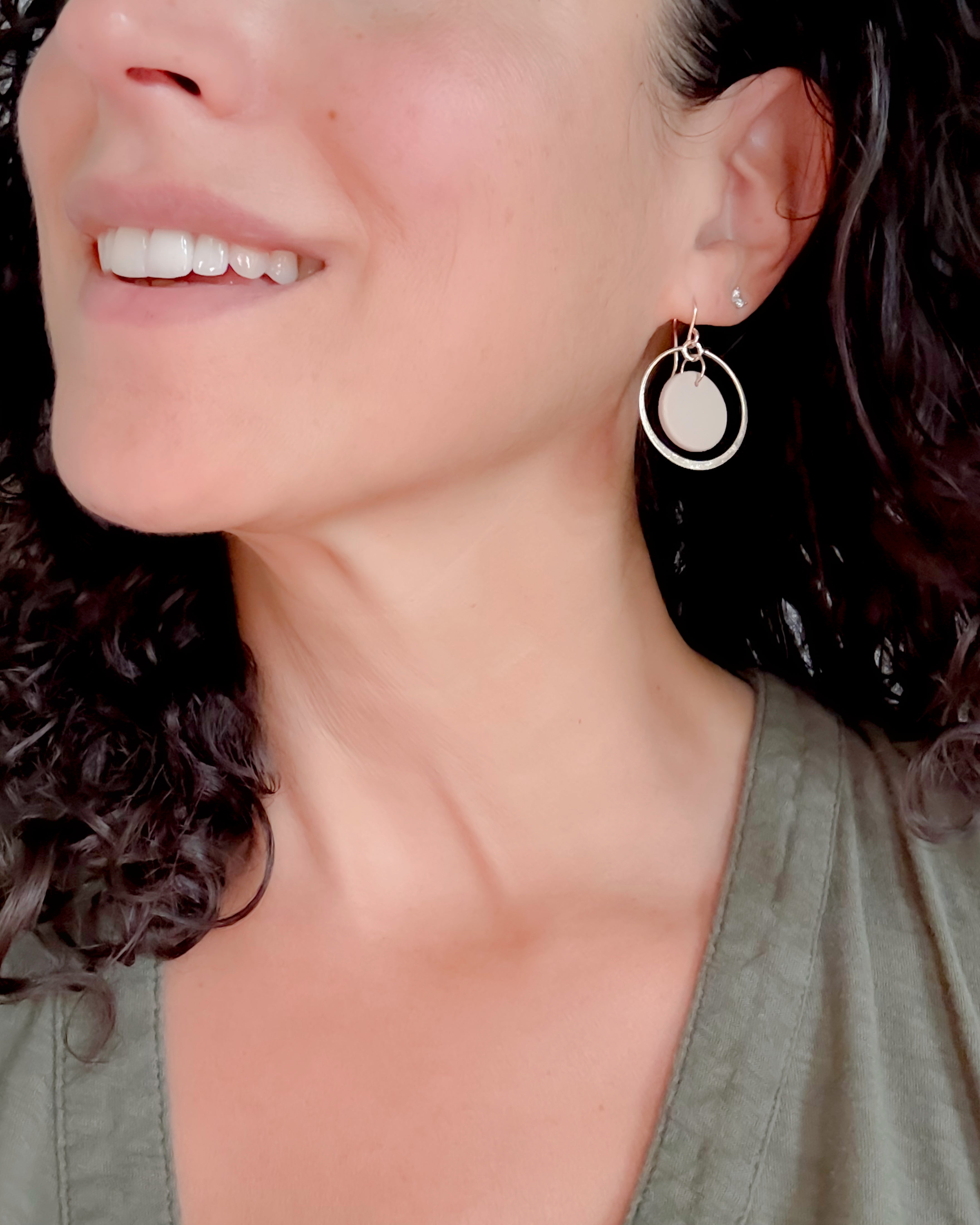 Close-up of a woman wearing gold hoop earrings with a neutral background