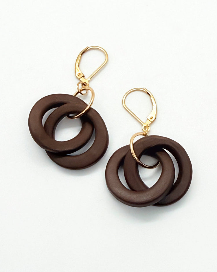 Pair of brown circular earrings with gold hooks on a white background