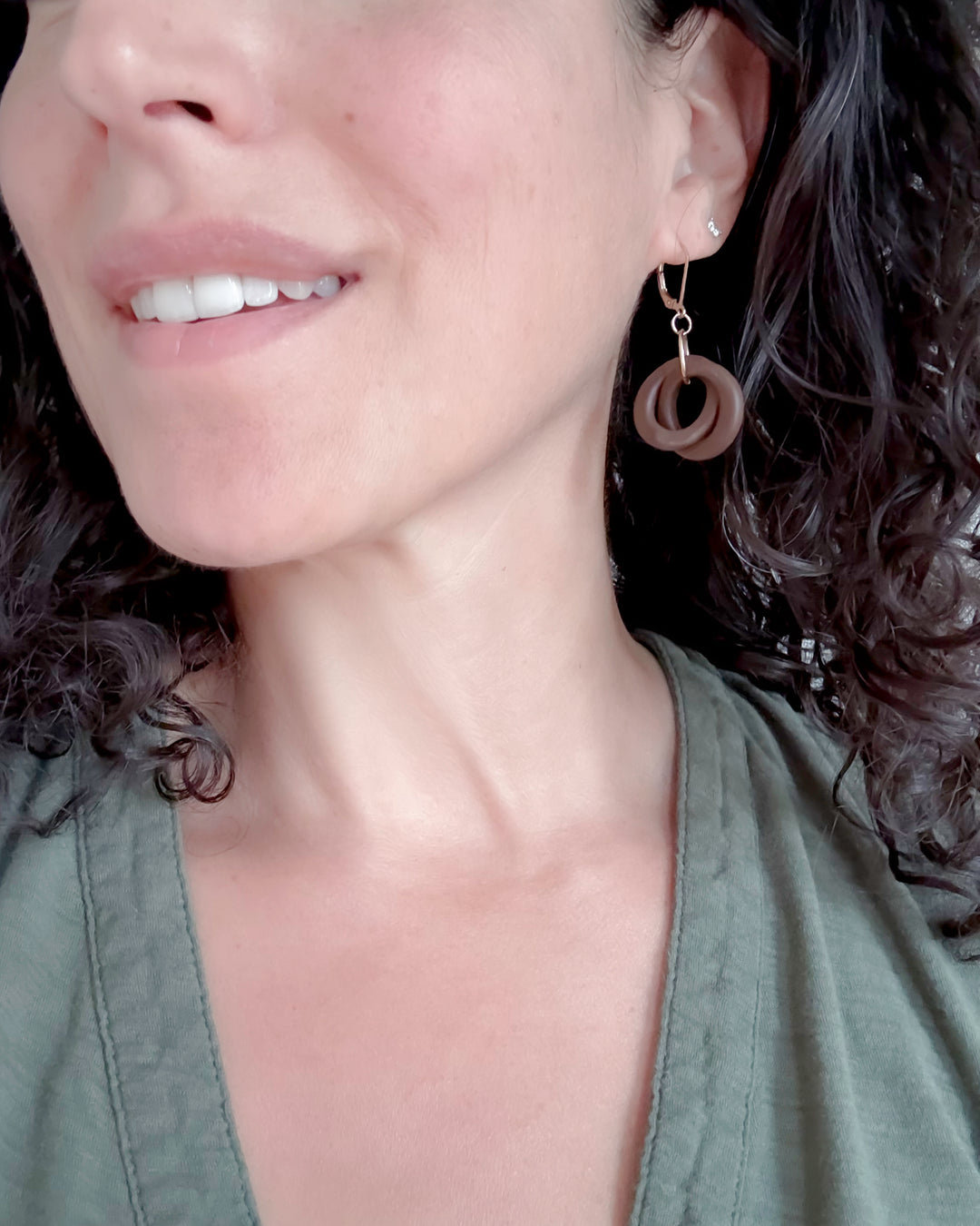 Close-up of a person wearing wooden hoop earrings with a neutral background