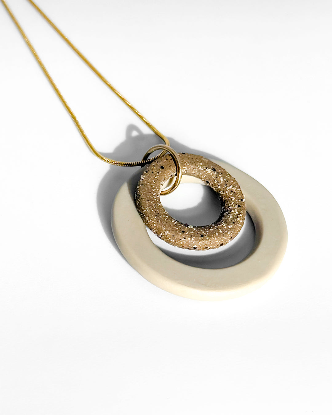 Gold necklace with a textured pendant on a white background
