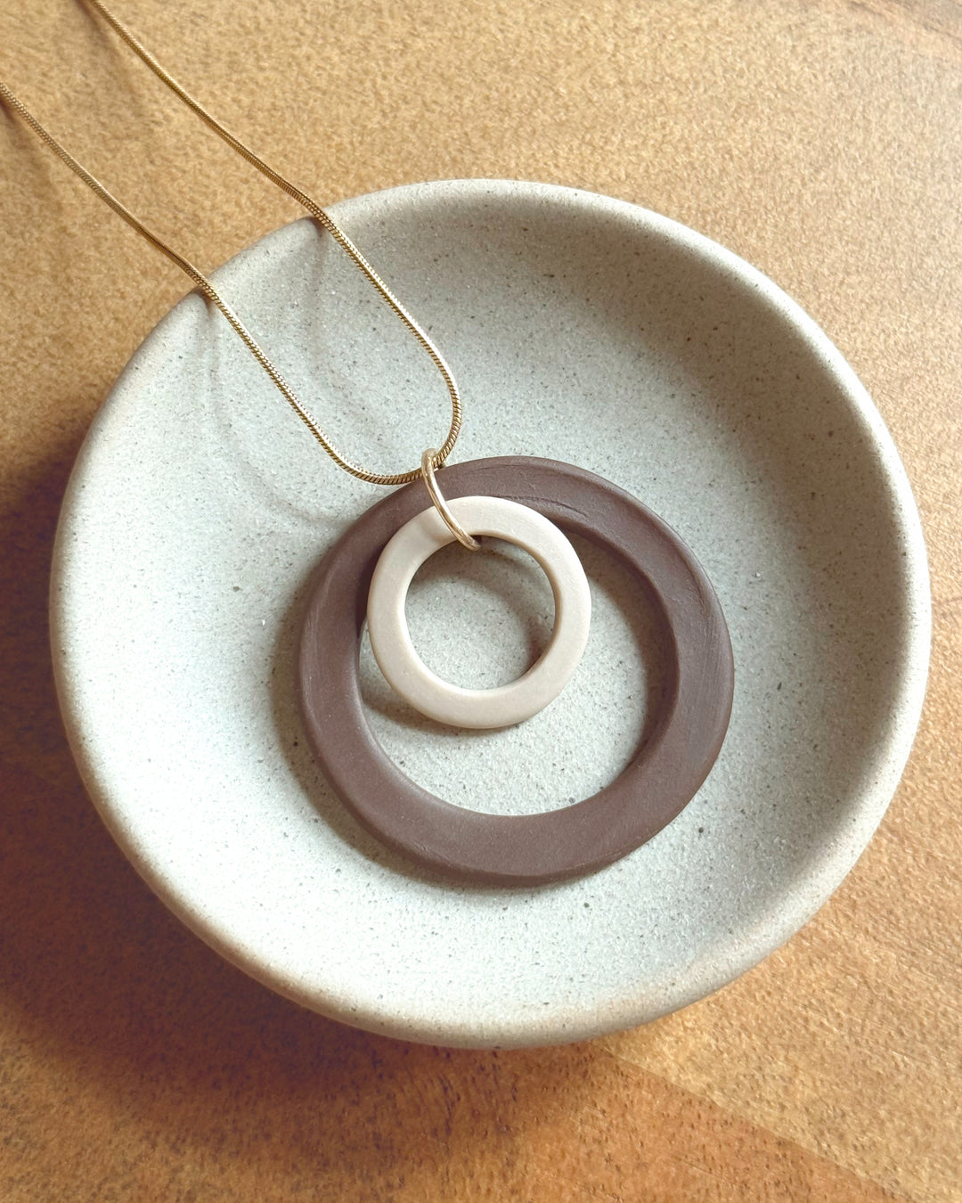 Necklace with a circular pendant on a textured beige surface