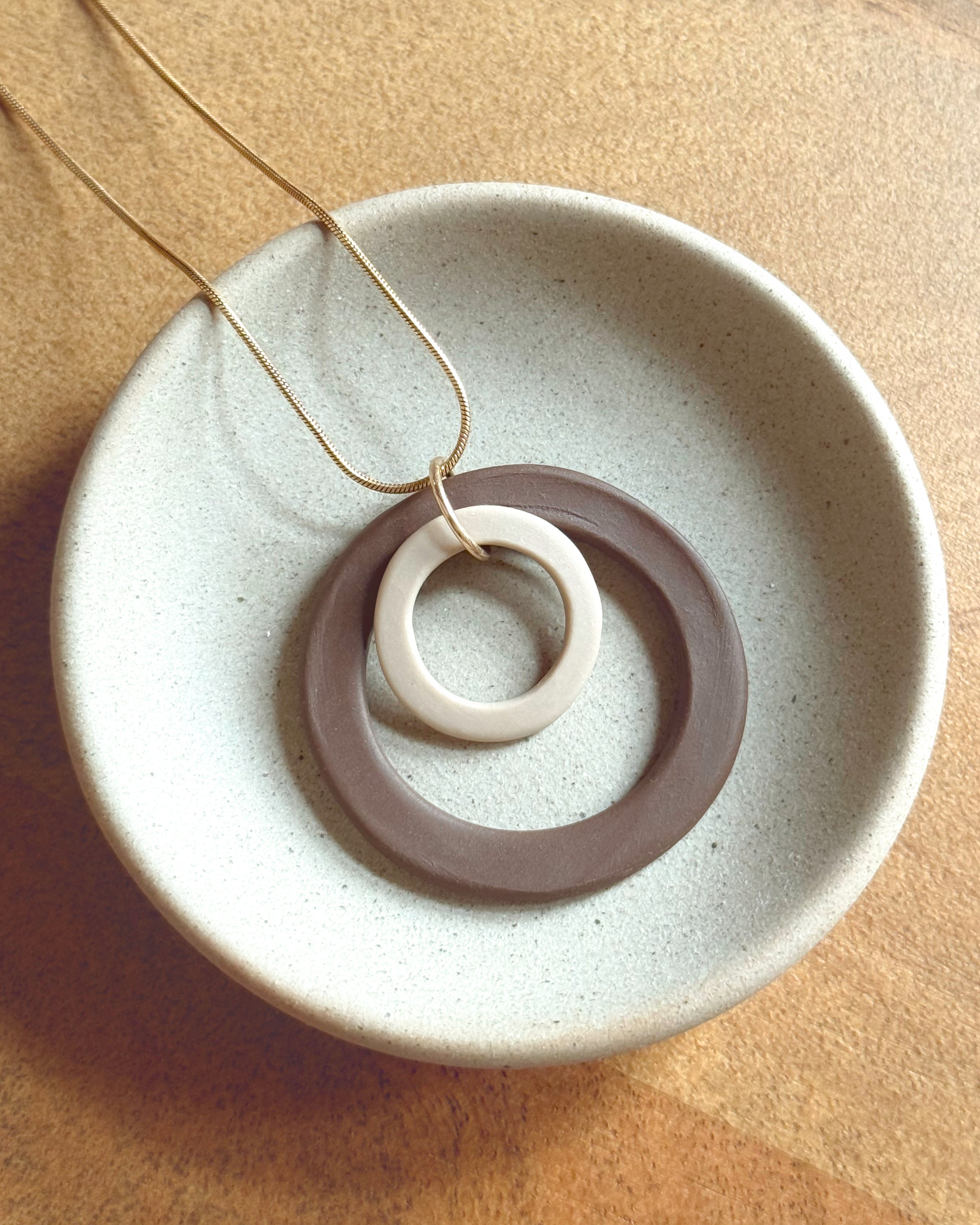 Necklace with a circular pendant on a textured beige surface