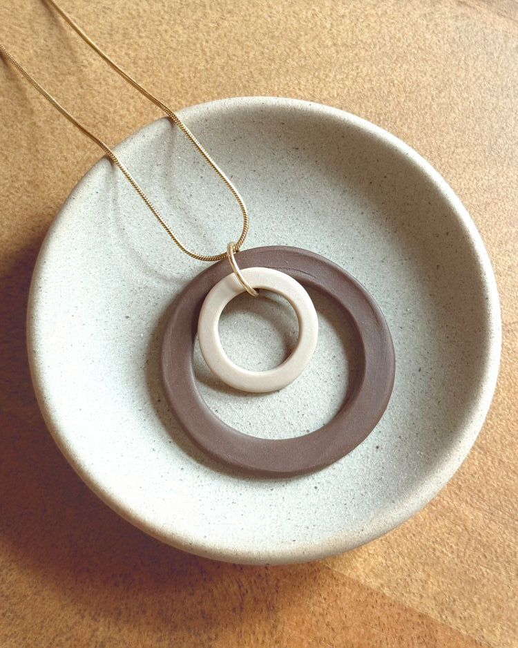 Necklace with a circular pendant on a textured beige surface