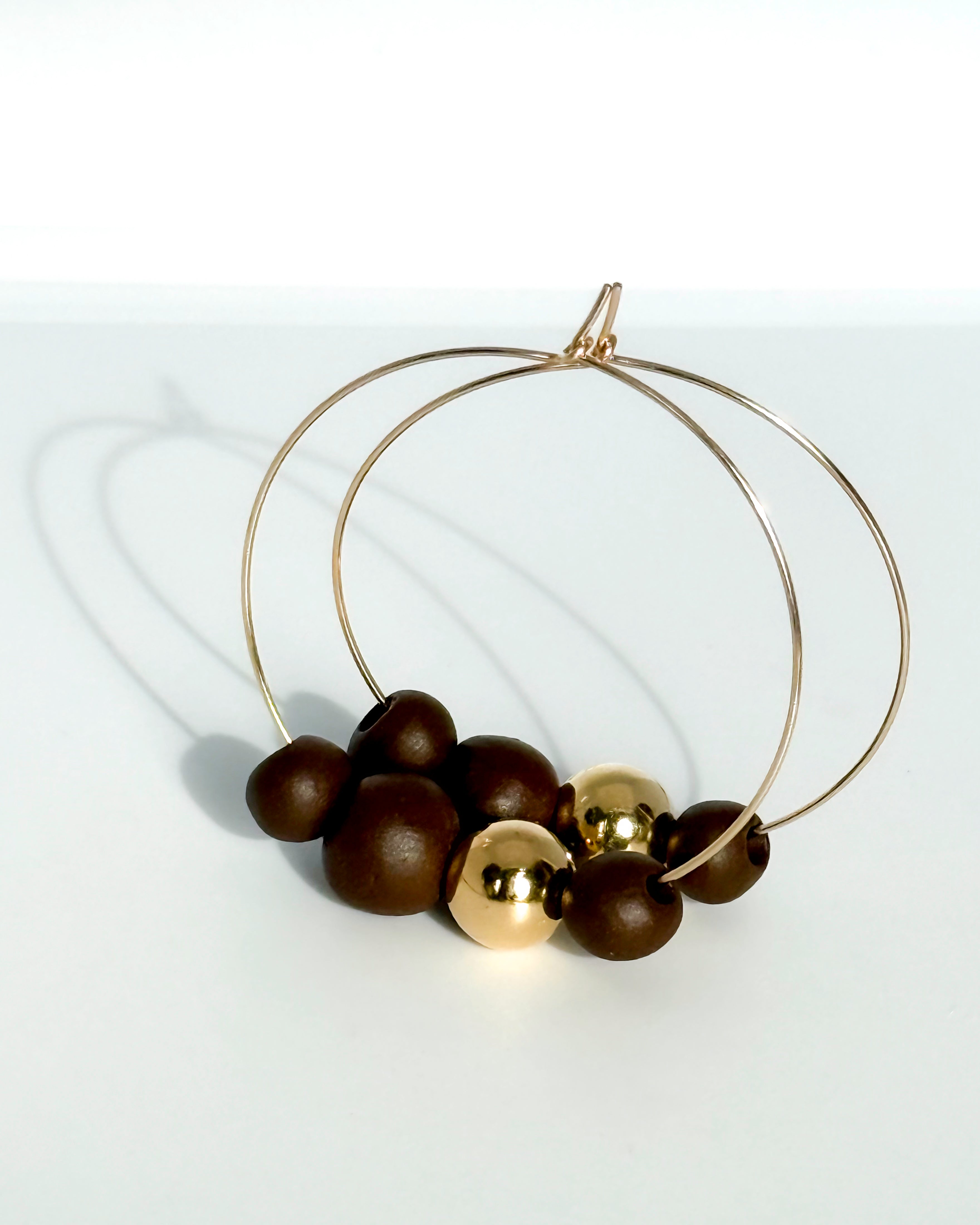Gold hoop earrings with dark beads on a white background