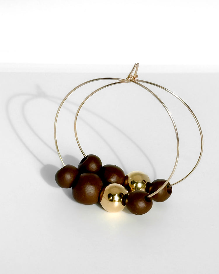 Gold hoop earrings with dark beads on a white background