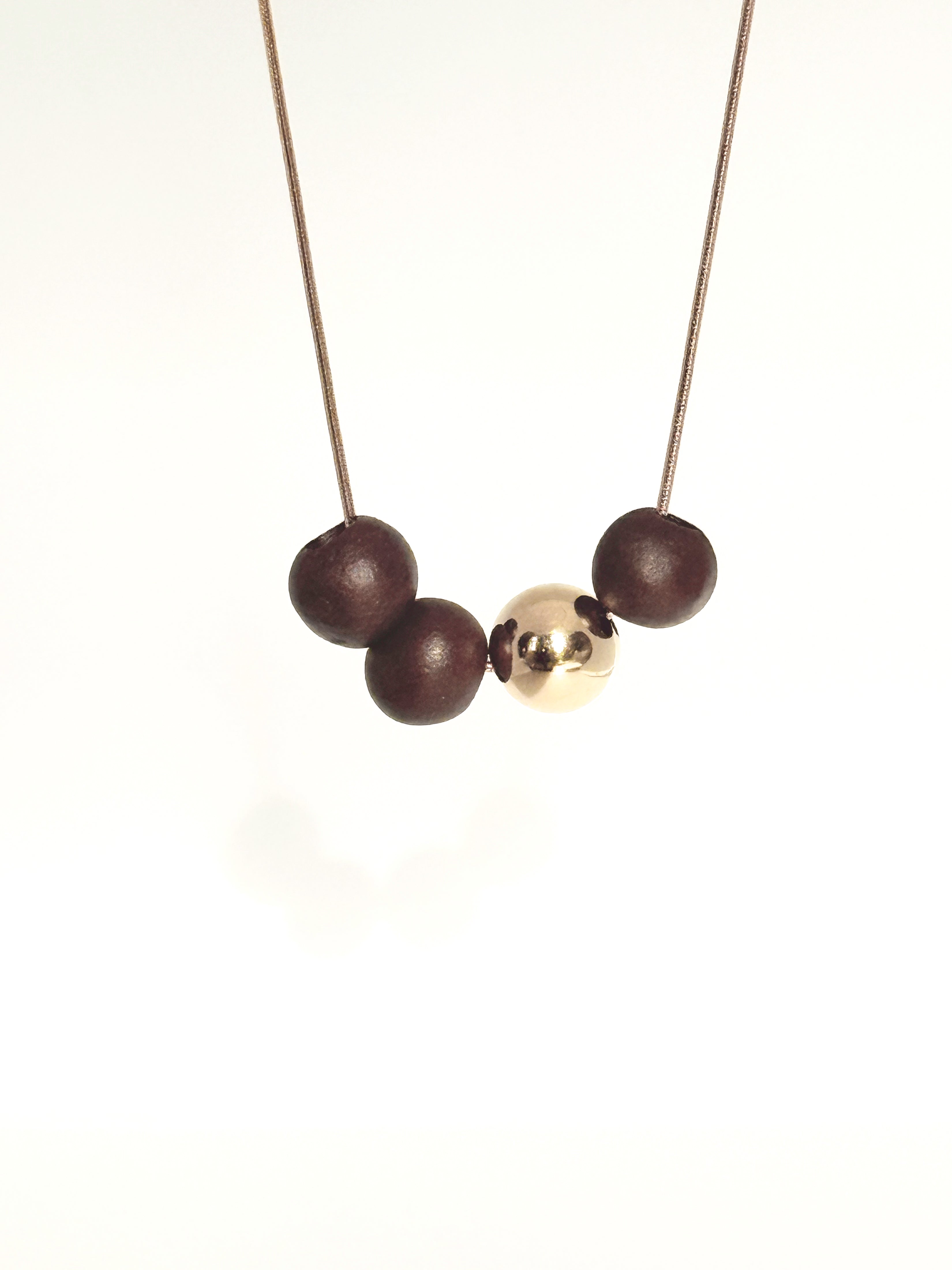 Necklace with three porcelain beads and a gold ball on a white background