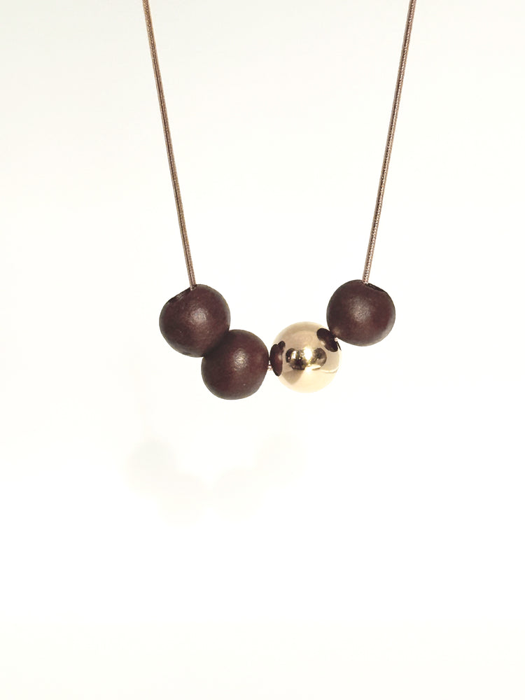 Necklace with three porcelain beads and a gold ball on a white background