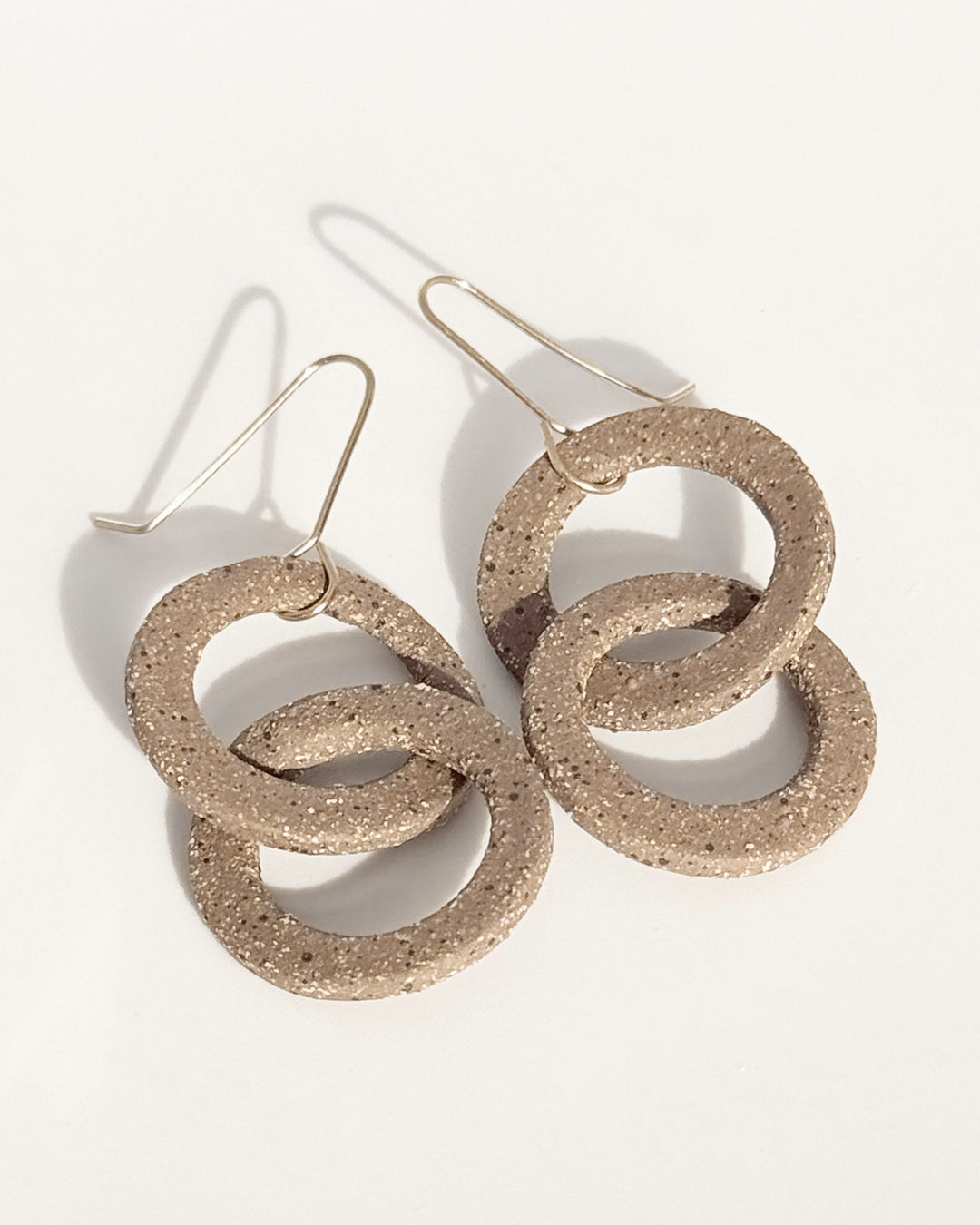 Pair of stoneware earrings with interlocking circular design on a white background