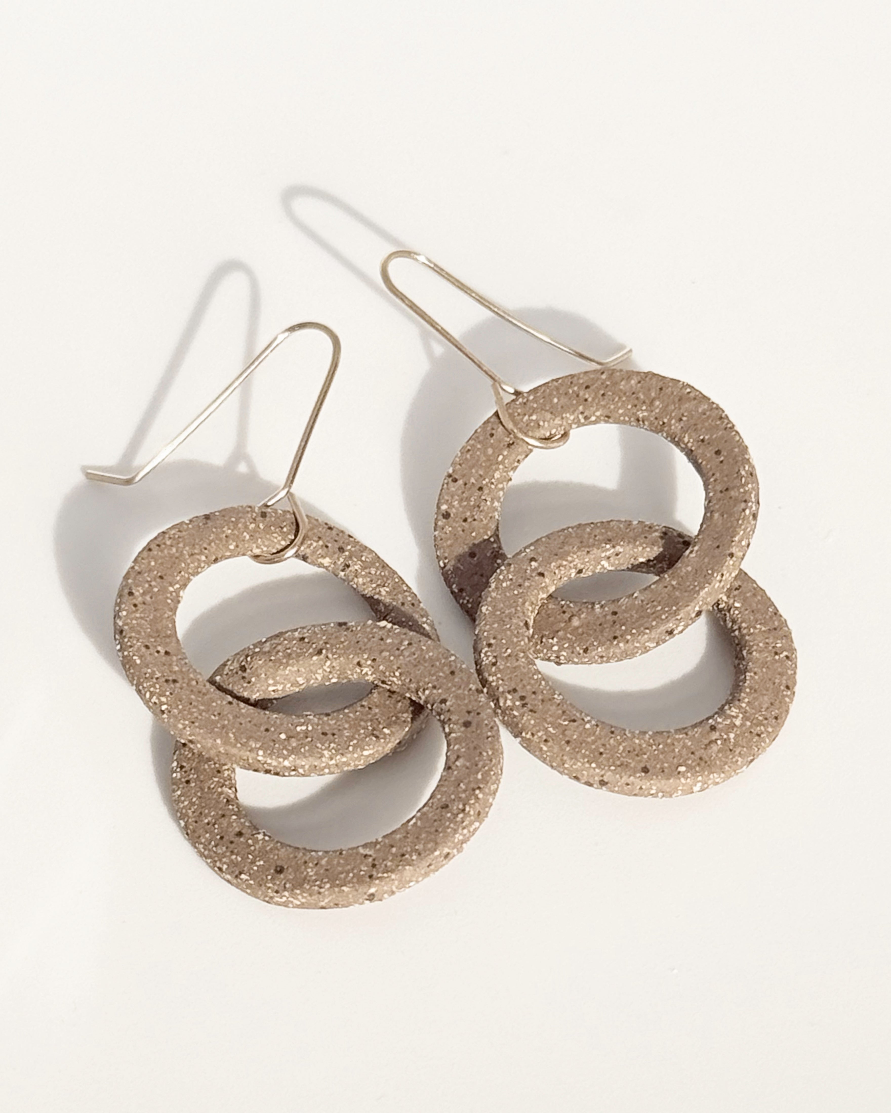 Pair of stoneware earrings with interlocking circular design on a white background