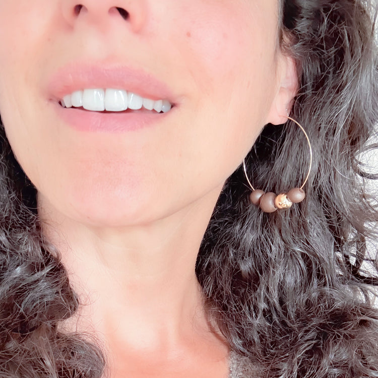 Close-up of a woman wearing gold hoop earrings with beads.