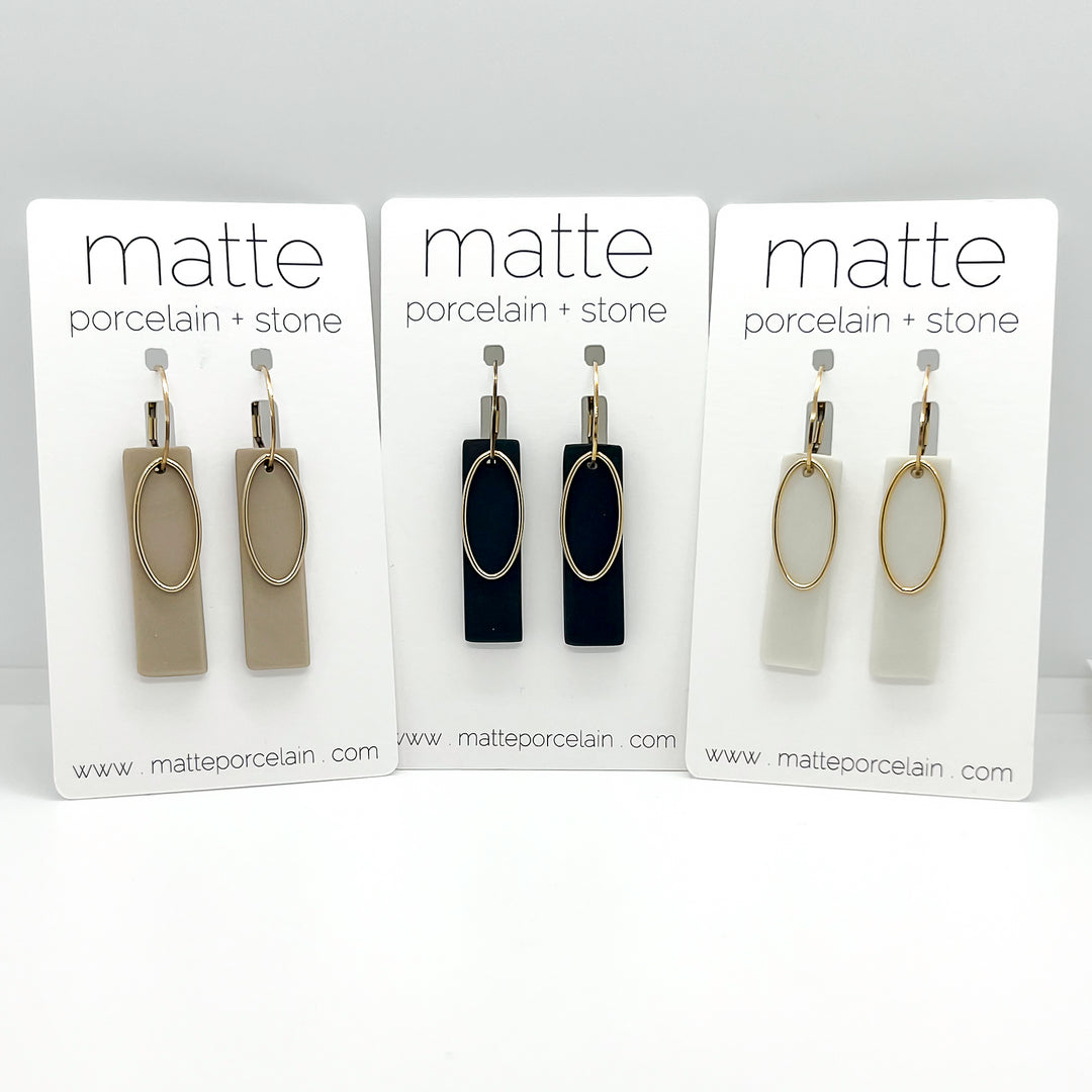 Three sets of earrings on display with 'matte porcelain + stone' branding.