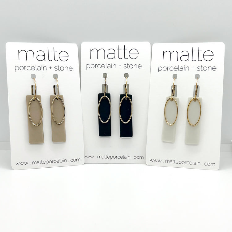 Three sets of earrings on display with 'matte porcelain + stone' branding.